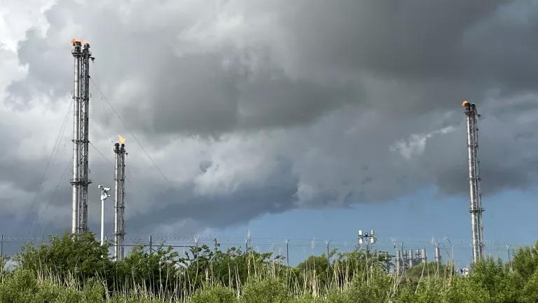 Gas is flared off from a liquefied natural gas (LNG) facility as storm clouds roll in