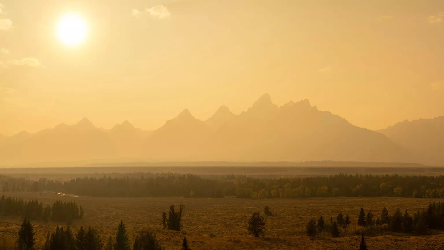A rugged landscape with mountains in the distance under a hazy, sunny sky
