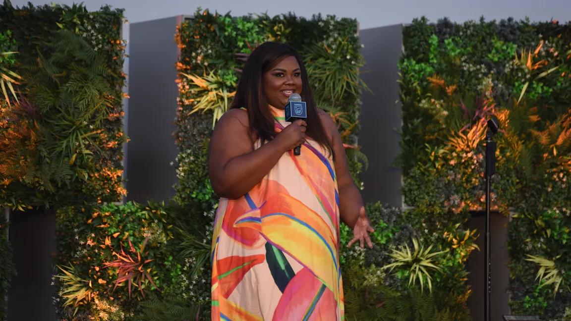 Nicole Byer holding a microphone and speaking