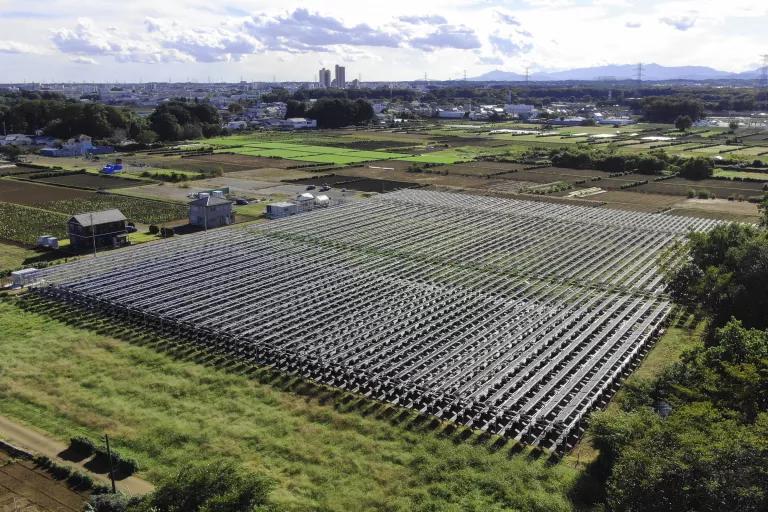 An aerial view of dozens of rows of solar panels installed on a grassy field