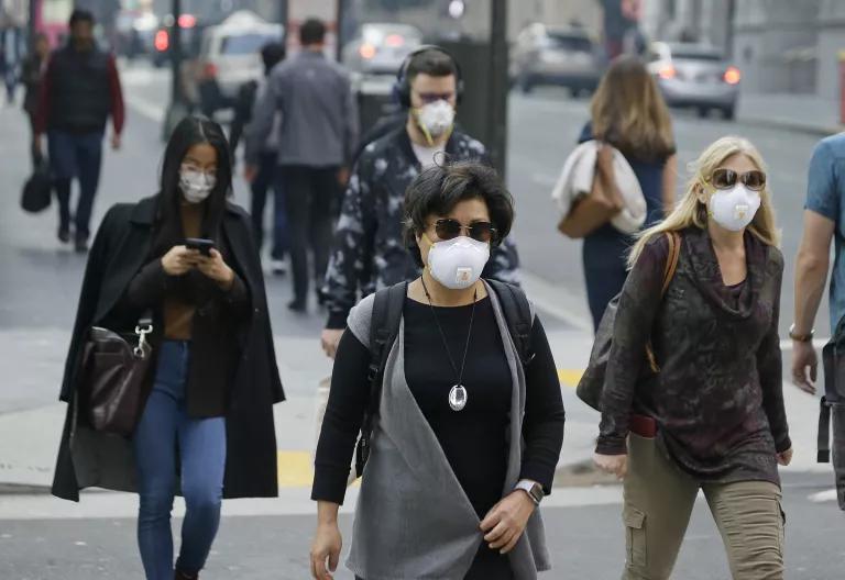 People wearing face masks walk on a city sidewalk