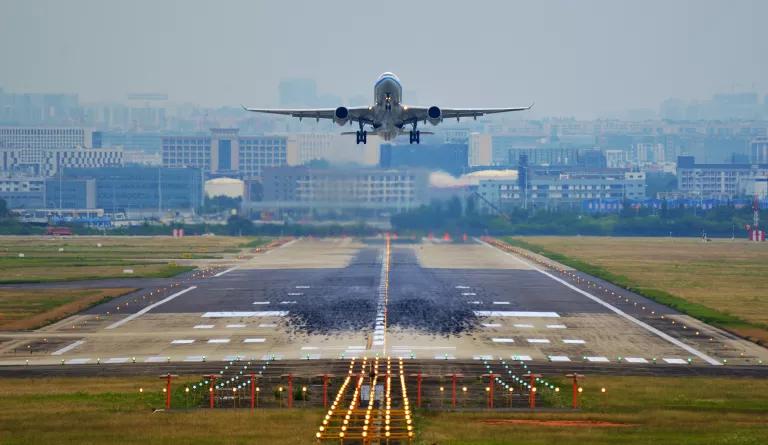 A large passenger plane flies just above an airport runway.