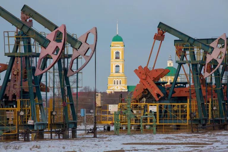 Oil rigs stand in front of a yellow church spire in the background