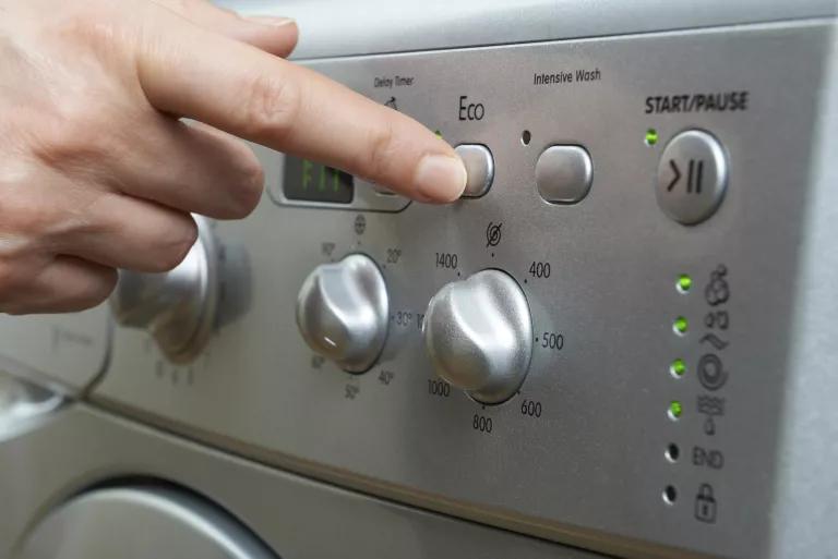A person pushes the "Eco" cycle button on a washing machine