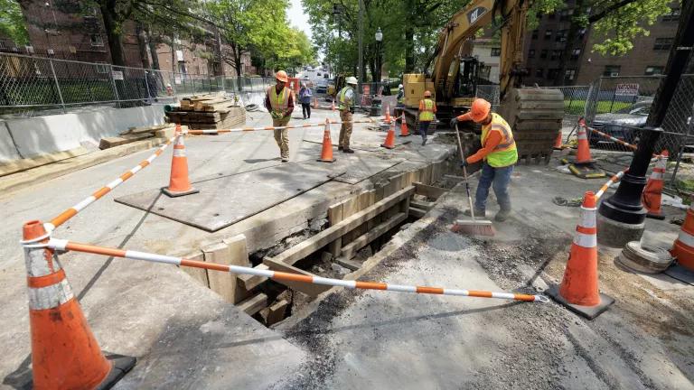 Construction workers break ground on a sewer project in a street closed to traffic.