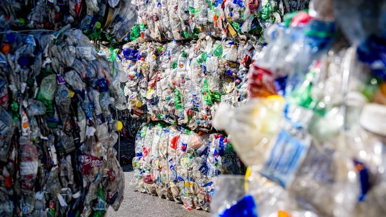 Bales of compressed plastic bottles piled up at a recycling facility.
