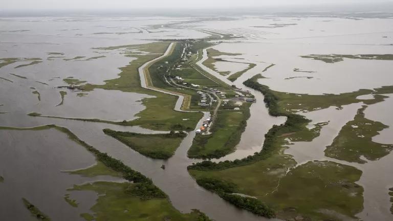 An aerial view of a marshland and a sliver of land with buildings on it