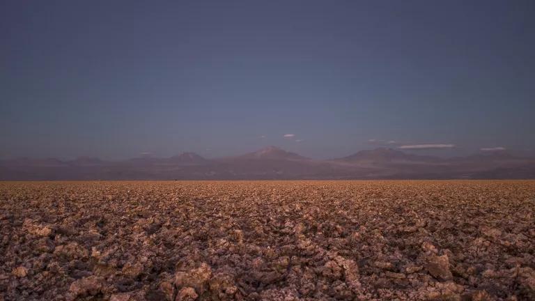 A flat brown expanse of land with mountains in the far distance