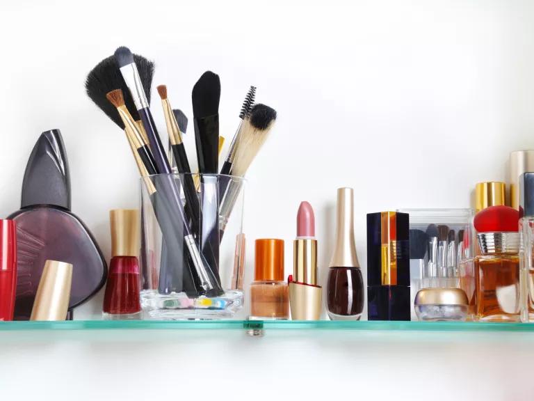 Cosmetics, brushes and toiletries on a bathroom shelf.