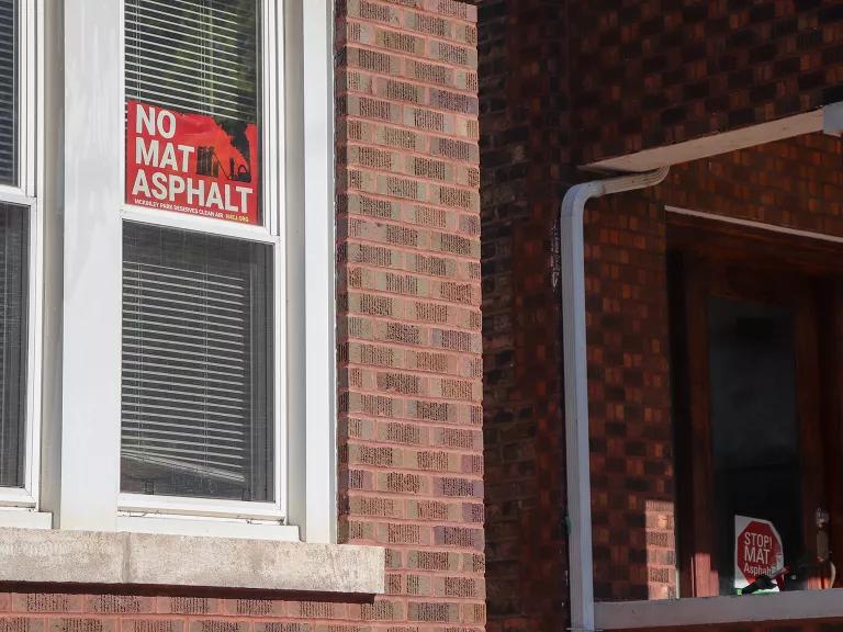 Signs saying “No MAT Asphalt” and “Stop MAT Asphalt” posted on homes in Chicago