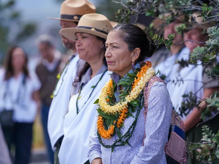 U.S. Department of the Interior Secretary Deb Haaland, with leis around her neck, standing alongside National Park Service rangers at Hawai’i Volcanoes National Park