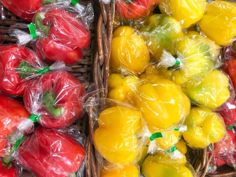 Red and yellow bell peppers wrapped in plastic packaging