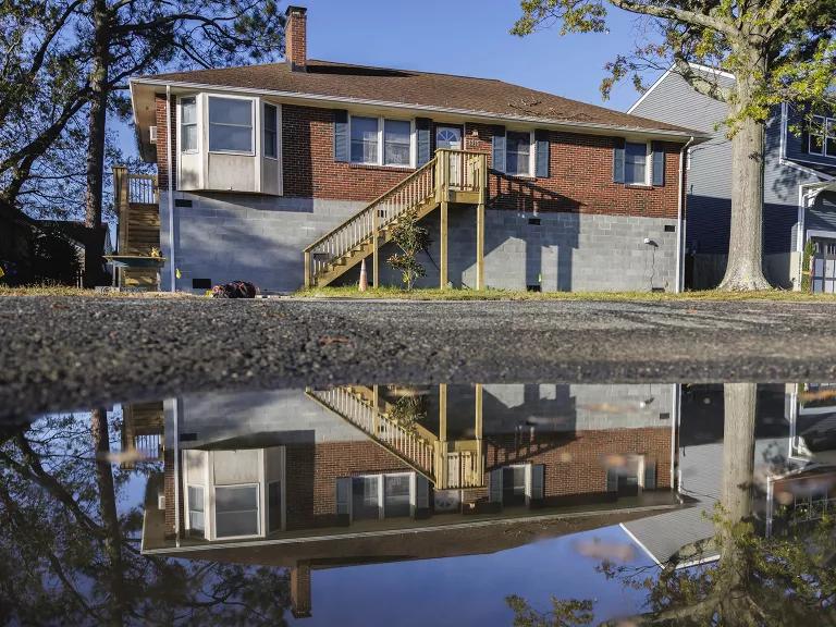 A home with an elevated foundation is reflected in water from high tide flooding in Norfolk, Virginia