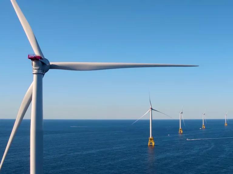 A row of wind turbines stand in the ocean