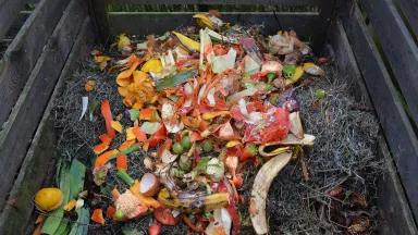 An overhead view of food scraps and yard waste in a compost bin