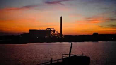 A power plant on the edge of a waterway at sunset