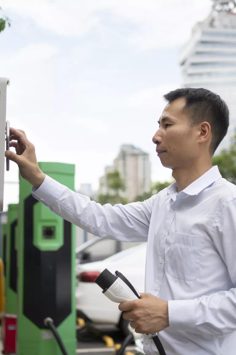 A man stands at an electric vehicle charging station.