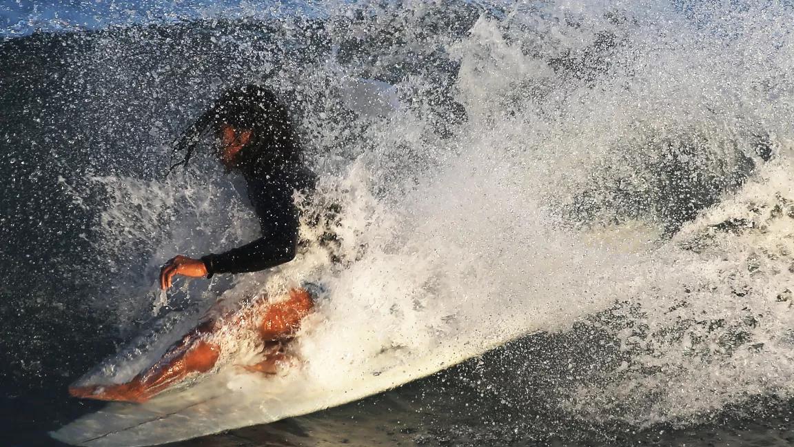 A surfer riding a wave at Surfrider Beach in Malibu, California