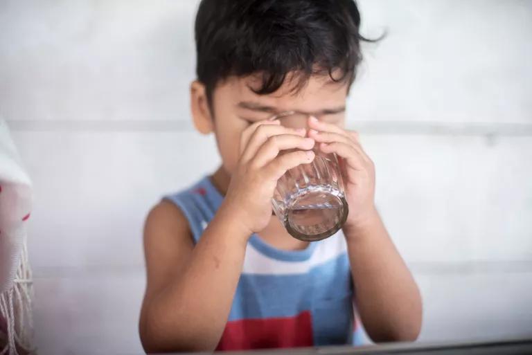 A young boy drinking water from a glass