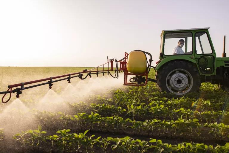 Tractor spraying pesticide over field
