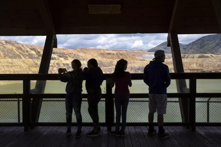 Four people stand in front of a large window overlooking a body of water