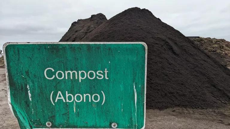 a pile of finished compost behind a green sign that reads "compost (abono)"