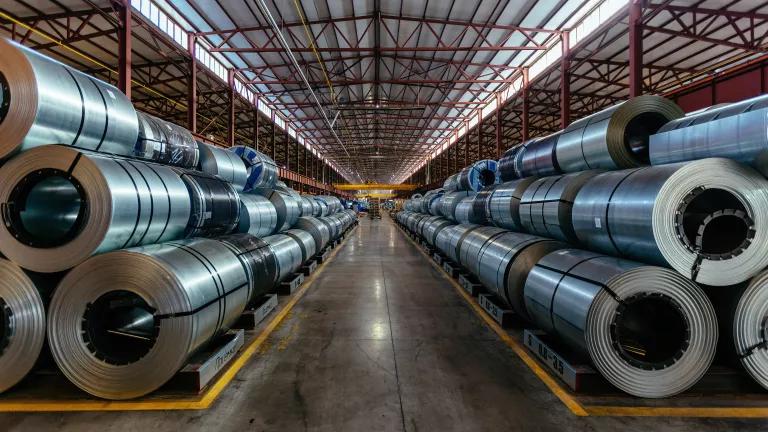 Rolls of galvanized steel sheet stacked in a warehouse.