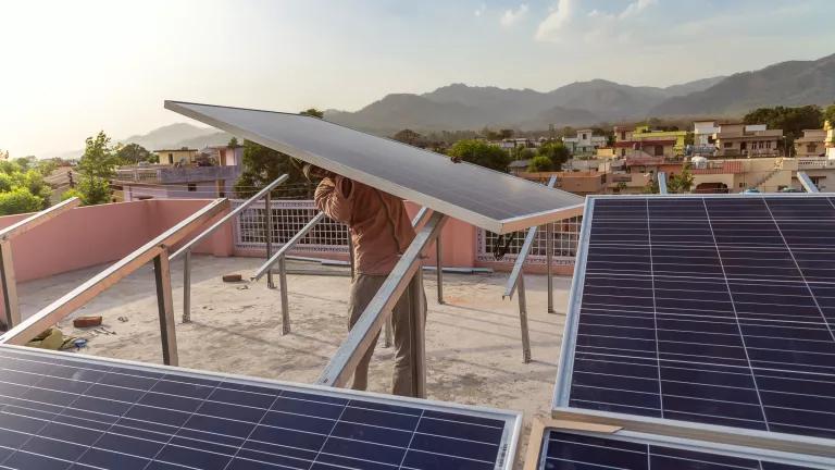 A man installs a solar panel on a roof array