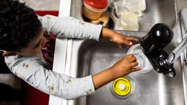 A boy fills a cup with water from the kitchen faucet in his Newark home.