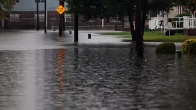 A flooded neighborhood street ends with a "dead end" sign.